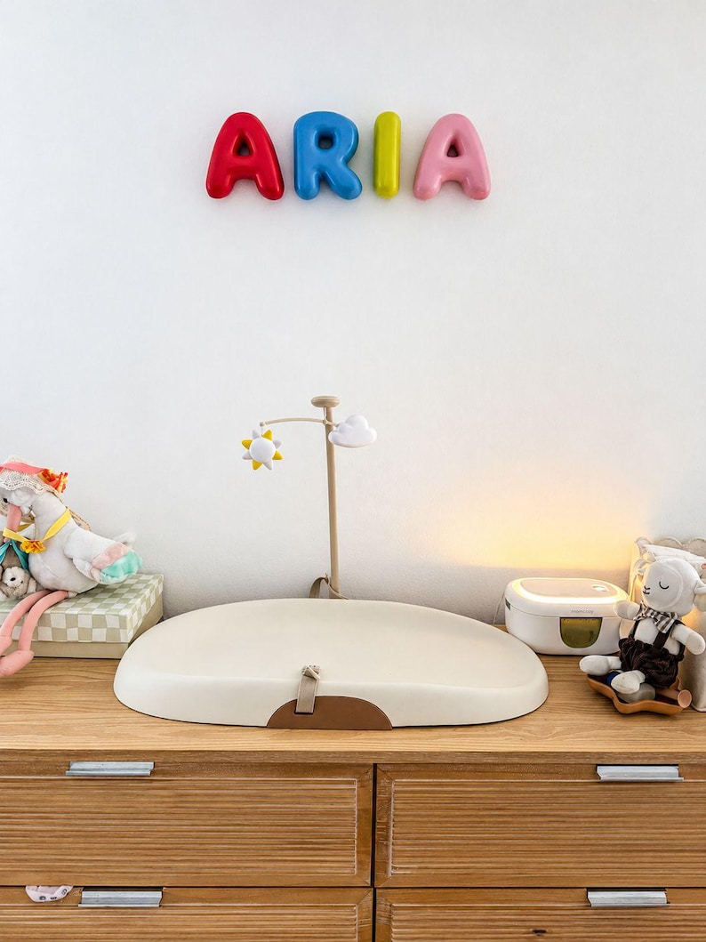 Custom 3D bubble letter name sign spelling ARIA above a nursery changing table